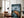 Large dark-framed mountain artwork leaning beside a brown armchair and floor lamp.
