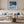 Black-framed Low Tide Light coastal print above a white sofa with pale blue cushions.