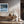 Black-framed Low Tide Light coastal print above a wooden console with dried branches and lanterns.