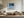 Black-framed Low Tide Light coastal print above a cream sectional sofa and low wood coffee table.