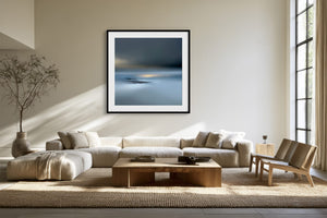Black-framed Low Tide Light coastal print above a cream sectional sofa and low wood coffee table.