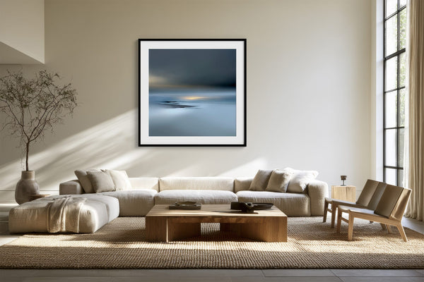 Black-framed Low Tide Light coastal print above a cream sectional sofa and low wood coffee table.