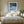Black-framed Low Tide Light coastal print centered above a bed with white bedding and wood nightstands.