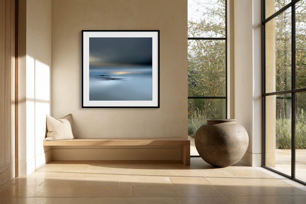 Black-framed Low Tide Light coastal print above a built-in bench beside large black-framed windows.