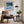 Black-framed Low Tide Light coastal print above a brown lounge chair, side table, and floor lamp.