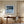 Black-framed Low Tide Light coastal print above a wood desk and upholstered office chair.