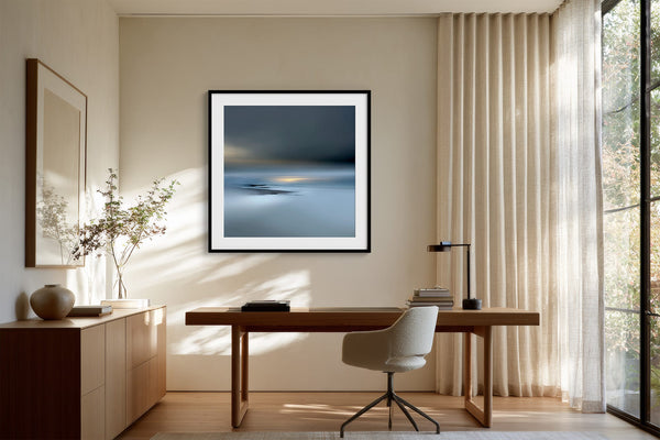 Black-framed Low Tide Light coastal print above a wood desk and upholstered office chair.