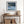 Black-framed Low Tide Light coastal print above a rustic console table with woven baskets.