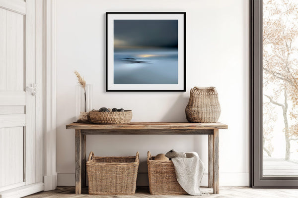 Black-framed Low Tide Light coastal print above a rustic console table with woven baskets.