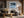 Black-framed Low Tide Light coastal print above a dark sofa in a room with exposed wood beams.