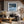 Black-framed Low Tide Light coastal print above a dark sofa in a room with exposed wood beams.