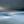 Soft-focus low-tide shoreline in blue-grey light with a narrow golden sunrise on the horizon