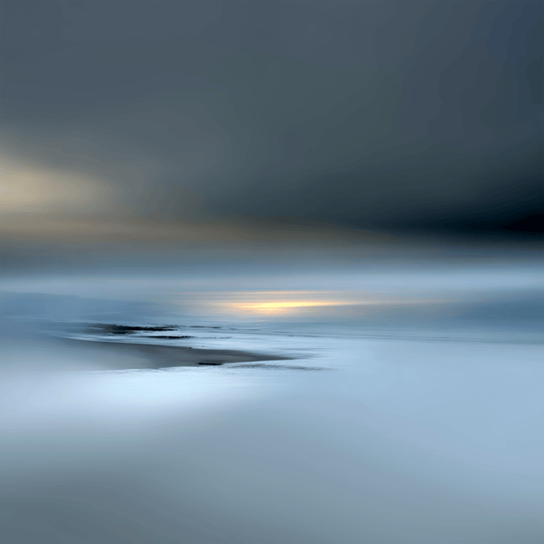Soft-focus low-tide shoreline in blue-grey light with a narrow golden sunrise on the horizon