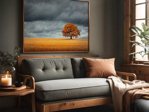 Oak landscape in a slim wood frame above a gray sofa beside a window.