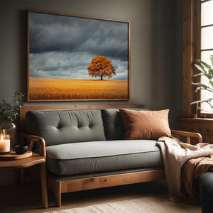 Oak landscape in a slim wood frame above a gray sofa beside a window.