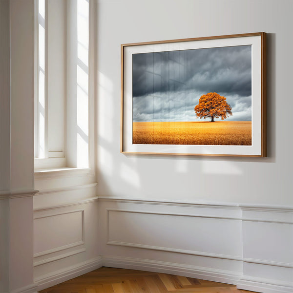 Wood-framed oak landscape print on a white paneled wall beside tall windows.