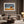 Framed oak landscape displayed above a cream sofa with dark curtains and floor lamp.