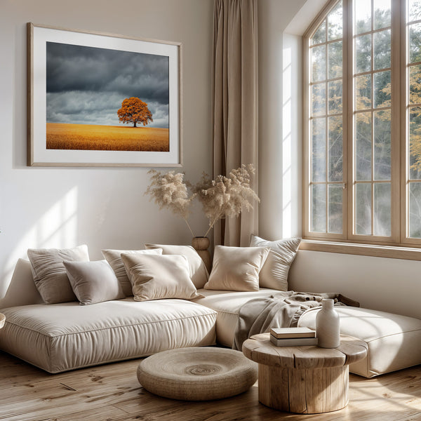 Solitary orange oak tree in a golden field beneath dark storm clouds