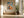 Framed geometric hare artwork above a built-in bench beside large black-framed windows.
