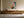 Framed geometric owl artwork above a low wooden sideboard with ceramic vessels.