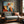 Geometric owl artwork in a slim wood frame above a gray sofa beside a sunlit window.