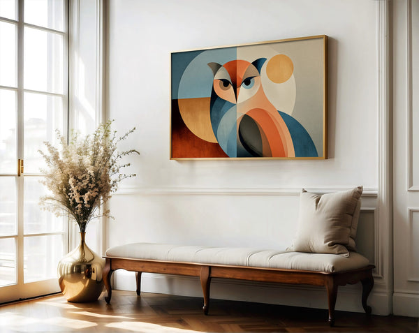 Framed geometric owl artwork above a cushioned wooden bench near tall windows and a vase of dried flowers.