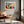 Geometric owl print in a light wood frame above a leather lounge chair beside large windows.