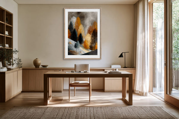 Framed winter tree artwork above a wooden desk in a sunlit neutral-toned workspace.