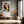 Framed winter tree artwork above a bench with an orange cushion in a sunlit corridor.