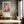 Light wood-framed geometric orange fox print above a bench in a sunlit hallway.