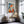 Thin gold-framed geometric fox print above a gold chair and glass side table.