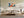 Light wood-framed orange fox artwork above a cream sectional sofa and low wooden coffee table.