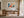 Light wood-framed geometric fox artwork above a wooden desk beside tall glass doors.