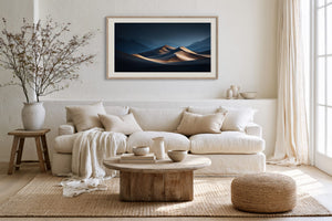 Light wood-framed desert dunes artwork above a cream sofa with a rustic coffee table.