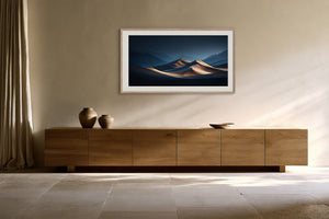 Light wood-framed desert dunes artwork above a low wooden sideboard with ceramic vessels.