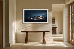 Light wood-framed desert dunes artwork above a rustic console table in a sunlit hallway.
