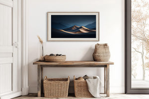 Light wood-framed desert dunes artwork above a weathered console with woven baskets.