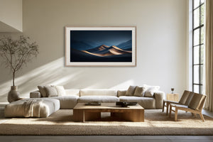 Light wood-framed desert dunes artwork above a low cream sectional and wooden coffee table.