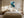 Framed teal, navy, grey and gold abstract artwork above a bed between two bedside lamps.