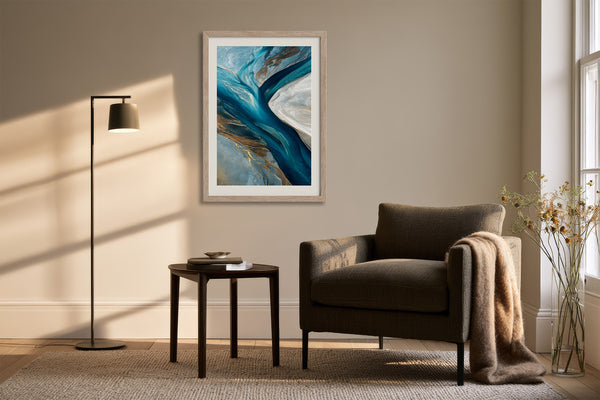 Framed teal and navy abstract artwork above a dark armchair, side table, and floor lamp.