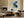 Framed blue and grey abstract artwork displayed above a low sofa beside a lit fireplace.