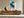 Framed blue abstract artwork above a long wooden sideboard with ceramic vessels.
