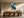 Framed teal and navy abstract artwork above a long wooden dining table with sculptural chairs.