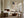 Framed beige and charcoal abstract artwork above a fireplace in a sunlit seating area.