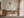 Framed beige and charcoal abstract artwork above a wooden desk beside tall windows.