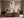 Framed beige and charcoal abstract artwork centered above a bed with dark wood nightstands.