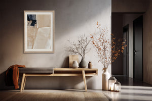 Framed beige and charcoal abstract artwork above a console table with dried branches and lanterns.