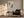 Framed beige, gray, and charcoal abstract artwork above an armchair beside a floor lamp.
