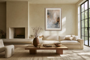 Framed textured abstract artwork above a cream sofa and low wooden coffee table.