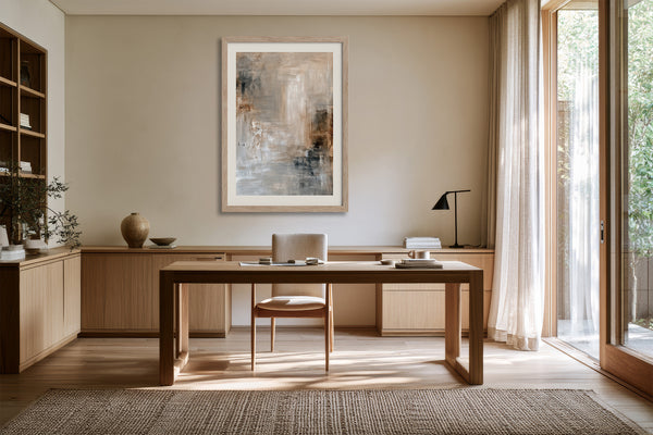 Quiet Layers II abstract print in a light frame above a wooden desk and chair.